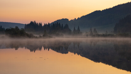 aube, lever de soleil avec brume sur le lac de Lamoura dans le Haute Jura 