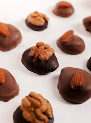 chocolate pieces with almond or walnut over in box or on table,one over another in pyramid.sweets candy on white surface,free space for text, ready for chocolate business or factory.