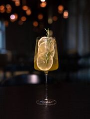 cocktail in glass with slice of lemons and rosemary against trendy modern restaurant with bokeh...