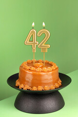 Number 42 birthday candle on a green background - Delicious cake with dulce de leche