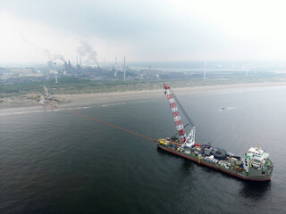 A vessel unrolls a seacable from an offshore windpark to an onshore power hub in Wijk aan Zee, the Netherlands. The wind farms are via cables or pipes to coastal area