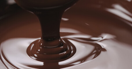 closeup pouring melted dark chocolate from spoon