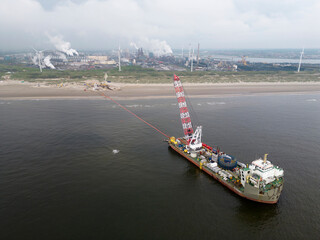 A vessel unrolls a seacable from an offshore windpark to an onshore power hub in Wijk aan Zee, the Netherlands. The wind farms are via cables or pipes to coastal area