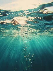 Naklejka premium Sunlight illuminating water bubbles in a tranquil ocean scene during midday, creating a serene underwater atmosphere
