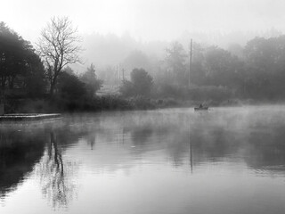 Scenic view of calm lake on a foggy autumn morning.Black and white