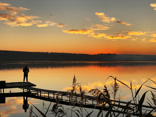 fisherman silhouette in the lake during sunrise. Beautiful sunset on the lake