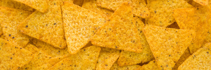 Yellow tortilla chips background. Closeup. Wide banner. Top down view.