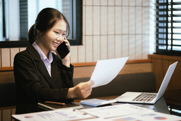 Asian businesswoman. She works with laptop and documents in the office.