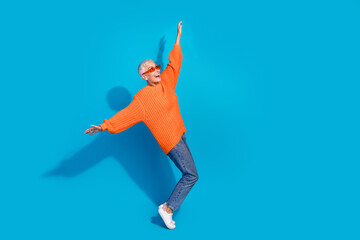 Photo of feel young old woman dancing carefree look empty space raise hands flying isolated blue color background