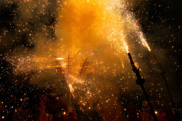 Obraz premium Group of demons that are part of a popular Catalan festival, with long sticks and strong firecrackers at the end, filling everything with fire and smoke,