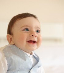 Baby boy smiling and wearing a blue waistcoat