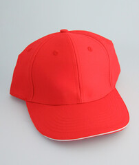 Red baseball cap with white brim on plain background