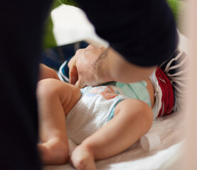 Father changing baby's diaper on changing table,