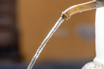 Fresh water flowing from a brass faucet in a public fountain