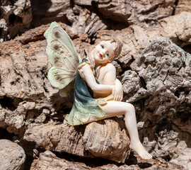 Fairy figurine sitting on a rock in a garden setting