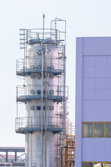 Industrial column tower with platforms and pipes in a chemical plant