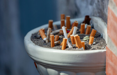 Full ashtray with many cigarette butts and ash outdoors