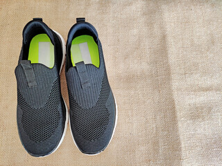 Black sports sneakers on a brown jute background
