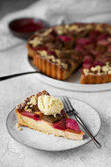 Rhubarb custard tart with geometric pattern and strawberry jam on a light stone table. A piece of cake with a scoop of ice cream. Spring and summer sweet-sour healthy dessert.