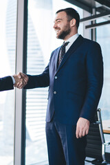 Smiling male entrepreneur shaking hand of worker