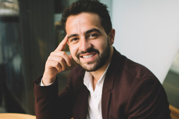 Portrait of handsome smiling businessman in formal wear using mobile phone for chatting online having break in cafe interior, positive successful male entrepreneur looking at camera enjoy devices