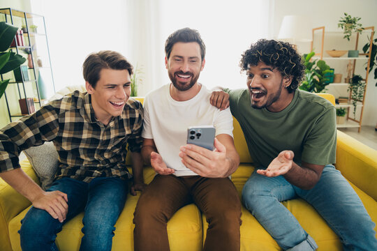 Portrait of three best friends use show smart phone gather chill free time modern interior flat indoors