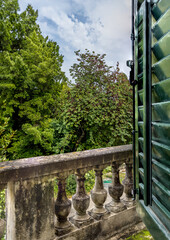 Balcony with a stone balustrade of an old historical palace leading to a park