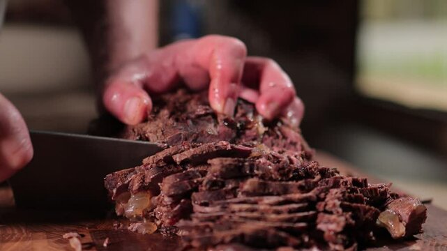 Male hands cutting cooked meat beef on a wooden board