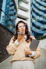 Naklejka premium Young businesswoman sending voice message in front of modern business building 