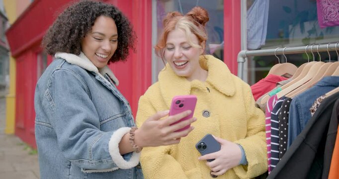 Female Friends Shopping and Looking at Phone at Vintage Clothes Shop