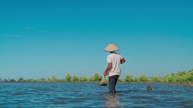 A fisherman carrying a fishing net on the shore
