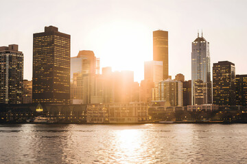 Fototapeta premium Cityscape at sunset, skyscrapers glow, water reflects urban beauty
