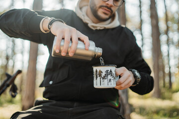 Young caucasian man drinking water taking break from hiking or trekking	