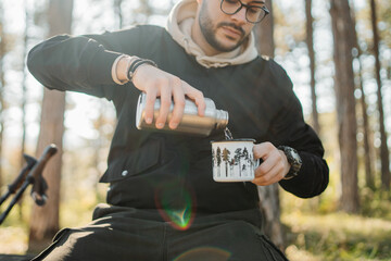 Young caucasian man drinking water taking break from hiking or trekking	