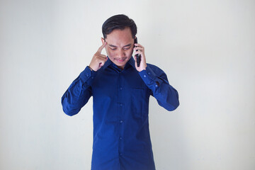 Asian man in blue shirt happy and excited thinking and concentrating while holding handphone. Asian student thinking and looking for ideas while holding phone over white background