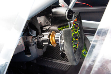 Close up of a race car cockpit showing steering wheel and controls