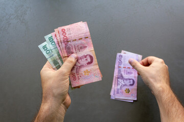 Man Counting Thai Baht Banknotes. A man holding and counting a stack of Thai Baht banknotes, focus...