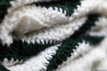 close-up of folded sage green zigzag blanket with white and hunter green accents, crocheted or...