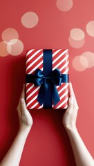 Obraz premium Female hands holding gift box on red bokeh background, top view. Copy space valentine, mother's day, birthday theme. Gift box with ribbon bow