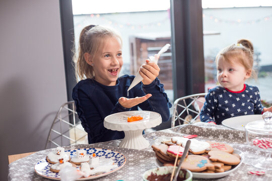 Sisters making "melting snowman" festive cookies with marshmallows