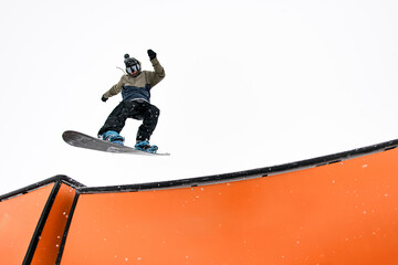 Snowboard pro executes jump into wallride, mastering challenging slope.