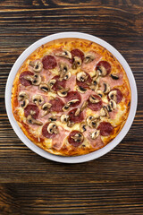 Top View of Pizza with Salami and Mushrooms on Dark Wooden Board