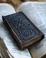 Obraz premium A vintage book with an ornate cover resting on open pages of another book.