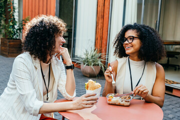 Female colleagues enjoying a lunch break in the office courtyard, sharing smiles and conversation...