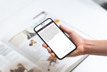 Hand holding smartphone scanning text in book, representing technology use for extracting...