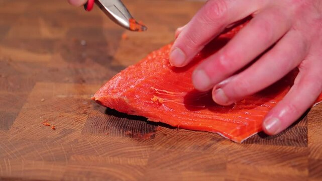 Male hands removing bones from red fish