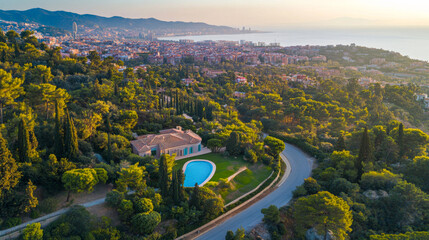 Aerial view of a villa with a pool surrounded by lush greenery overlooking a coastal city at sunset