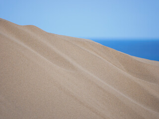Sand textured pattern with copy space close up in Maspalomas, Gran Canaria. Abstract background wallpaper. Sand waves in a desert dune at the background of the sea