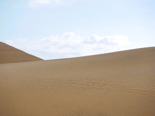 Sand textured pattern with copy space close up in Maspalomas, Gran Canaria. Abstract background wallpaper. Sand waves in a desert dune against the sky