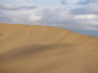 Sand textured pattern with copy space close up in Maspalomas, Gran Canaria. Abstract background wallpaper. Sand waves in a desert dune against the sky